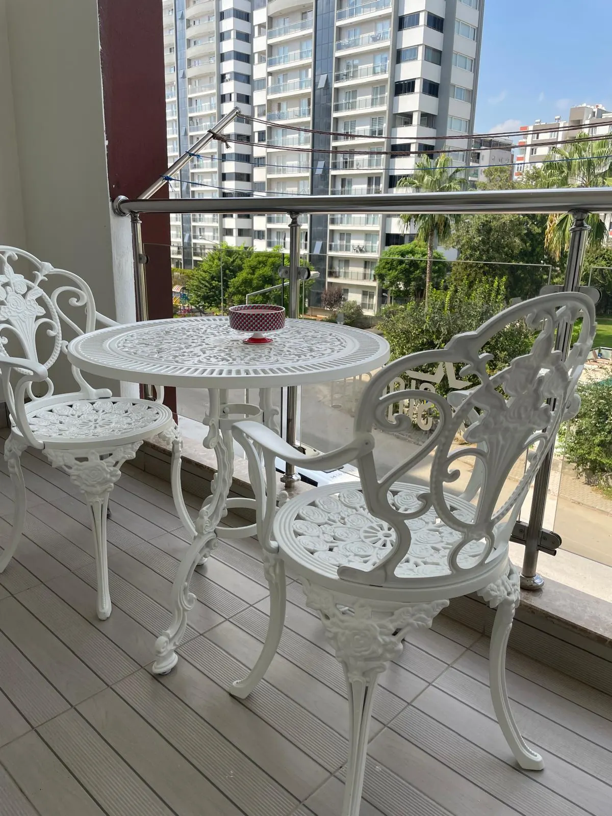 Havuz manzaralı balkonda beyaz döküm bistro masa ve sandalyeler