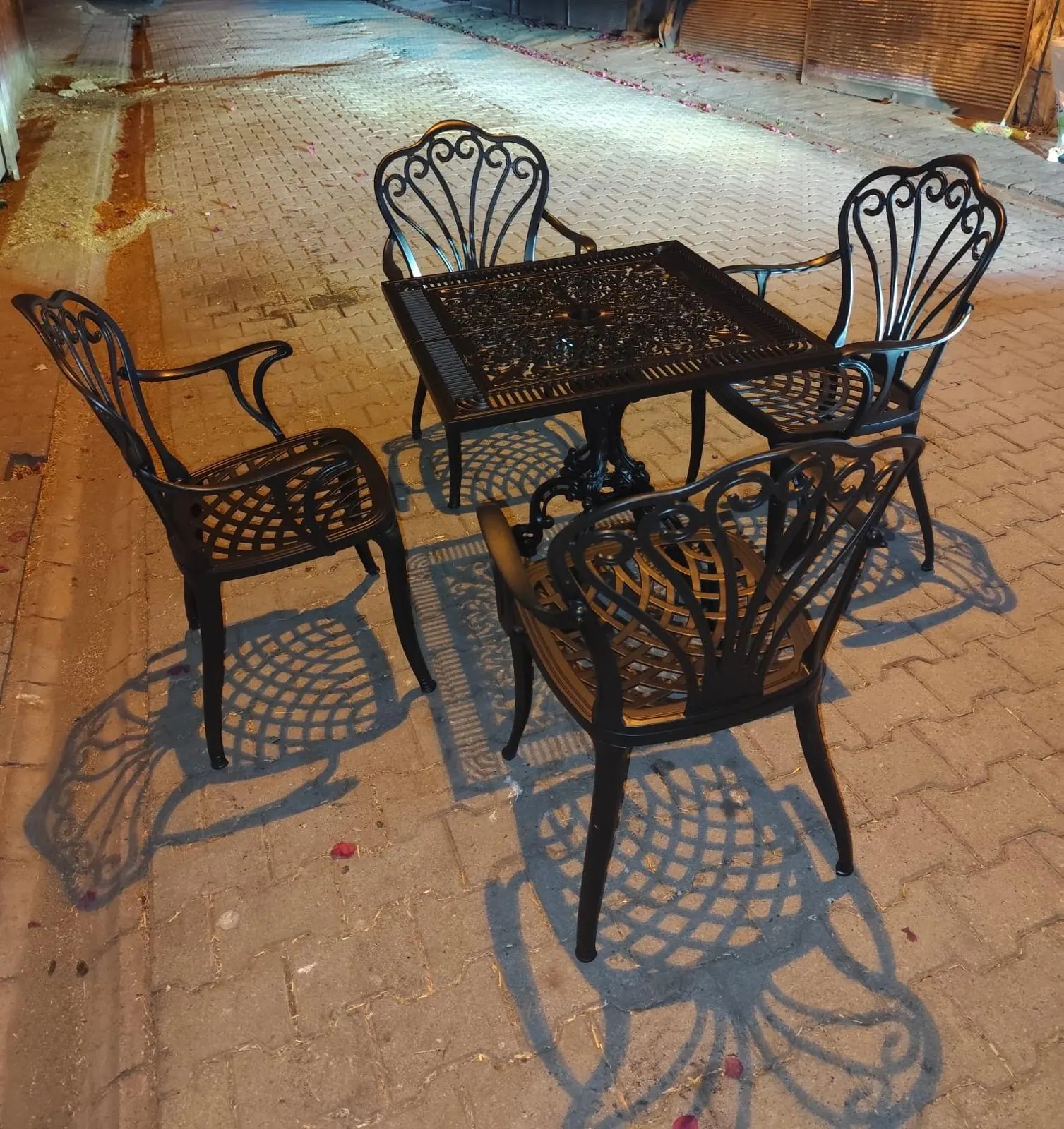 Dış mekanda siyah döküm kare masa ve dört sandalye